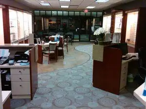 An indoor office space featuring a circular carpet, tables, chairs, and decorative elements, creating a welcoming and professional atmosphere.