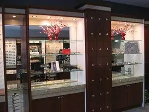 A view of an interior of a shop with wooden cabinets, glass shelves, and decorative items on display.