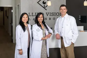 Three people in white coats standing in front of a reception area at Allio Vision in Lisbon
