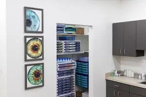 An empty room with three picture frames and a cabinet with many things on it.