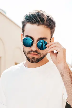 A man with brown hair wearing a white t-shirt and sunglasses with blue tints.