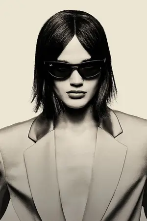 A woman wearing sunglasses and a suit poses for a photo