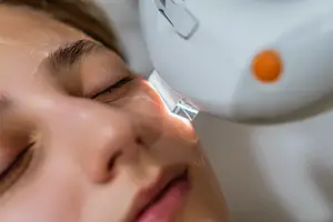 A woman is receiving a facial treatment with a laser device.