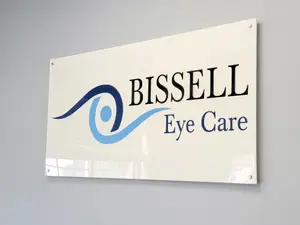 A white sign with the text 'BISSELL Eye Care' in blue and black fonts is mounted on a wall.