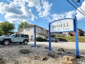 A white Jeep is parked in front of the Bissell Eye Care building on a sunny day with a clear blue sky.