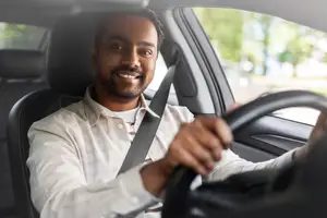 Man smiling while driving a car on a sunny day