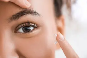 Woman placing contact lens in her eye