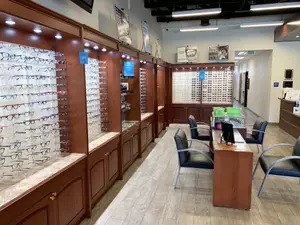 A shop interior with rows of glasses on display and chairs near a monitor on a desk