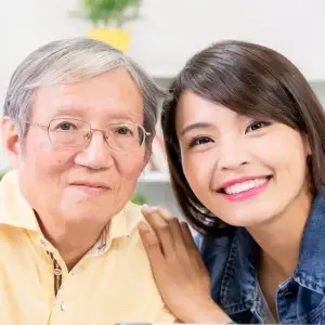 An older man and a young woman smiling and posing for a picture