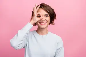 A smiling woman making a peace sign gesture with her hand and smiling for a photo