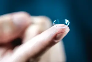 A person holding a contact lens in their hand