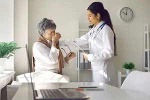 an elderly woman with a doctor examining her eyes in an office