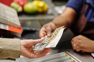 A person handing a coupon to a cashier at a checkout counter.