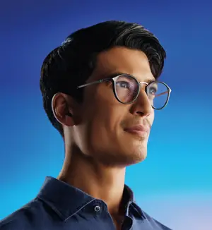 A man wearing glasses and a blue shirt looking upwards
