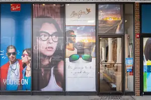 An image of an outdoor shop with posters on the glass windows and a glass door. There are images of people wearing sunglasses, and the text reads You're on, Aloha, and Maui Jim.
