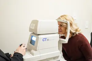 Woman undergoing eye test using CT-80 auto refractor machine