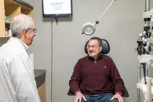 A doctor examining a patient in a clinic with medical equipment and a monitor
