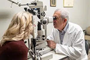 Doctor examining woman's eyes using an ophthalmoscope