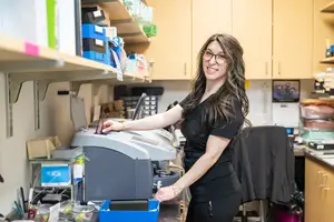 Woman in lab coat working with a printer