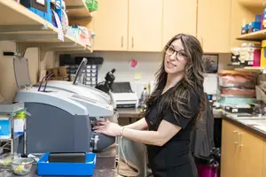 A woman working in a lab wearing glasses and a black top