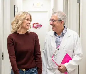A doctor and a woman smiling at each other in a hallway
