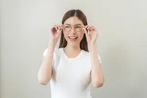 Young woman adjusting glasses and smiling