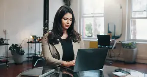 A woman working on a laptop in an office room