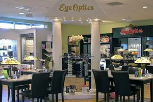 The interior of an Eye Optics shop with several black chairs, tables, and lamps, along with some decorative items.