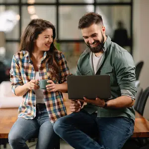 A man and a woman sitting on chairs in front of a table and a laptop