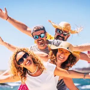 Three people with wide smiles and arms outstretched on a beach