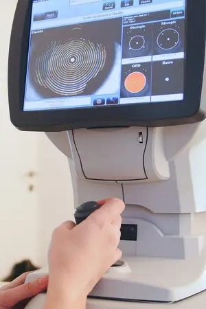 A person adjusting a medical device with a screen displaying various eye examination settings and a circular image of an eye.