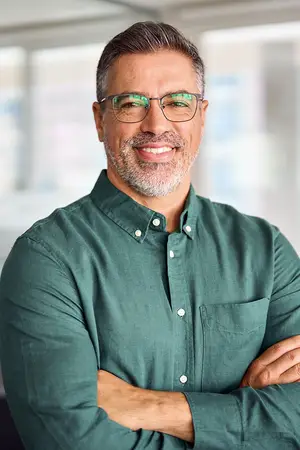 A man wearing a green shirt and glasses smiling at the camera