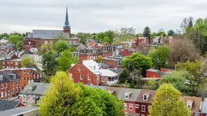 An aerial view of a neighborhood with many buildings, trees, and a cloudy sky in the distance.