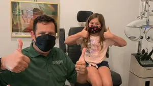 A man and a girl giving a thumbs up in a clinic