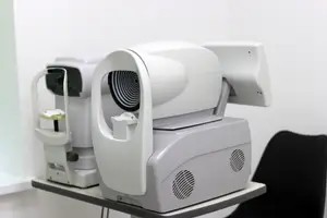 An electronic device that is probably an eye scanner with a black chair behind it.