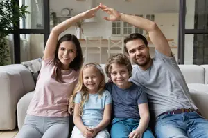happy young couple and children sitting on sofa