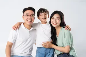 A smiling family of three, a man, a woman, and a young boy, posing together