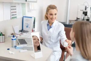 A female optometrist is examining a young girl's eyes in a clinic.
