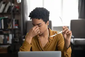 woman sitting at her laptop with irritated eyes