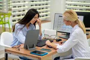 A woman is consulting with an optometrist about her eye health in an optical shop.