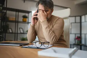 man at desk on phone talking with his optometrist