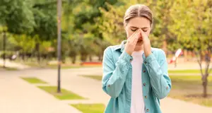 woman covering her face with her hands in a park