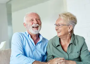 Senior couple sitting on a couch smiling at each other