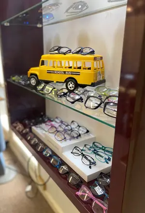 A display case filled with various colored glasses and a yellow school bus toy placed on top of the case.