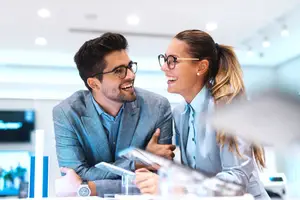 A smiling couple in a suit sitting at a table in a business room