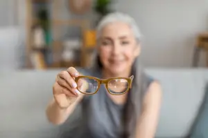 A woman is holding a pair of glasses in her hands