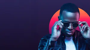 A man adjusting his sunglasses and posing for a photo with a colorful background