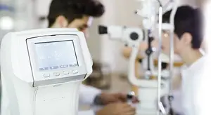 A young man is getting his eyes examined by an eye doctor using a machine in a hospital room