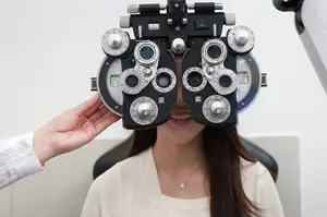 A woman is having her eyes checked by an optometrist using an eye exam machine