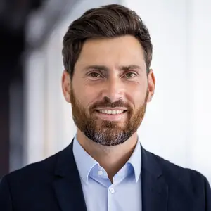 Photo of a man in a business suit smiling for the camera